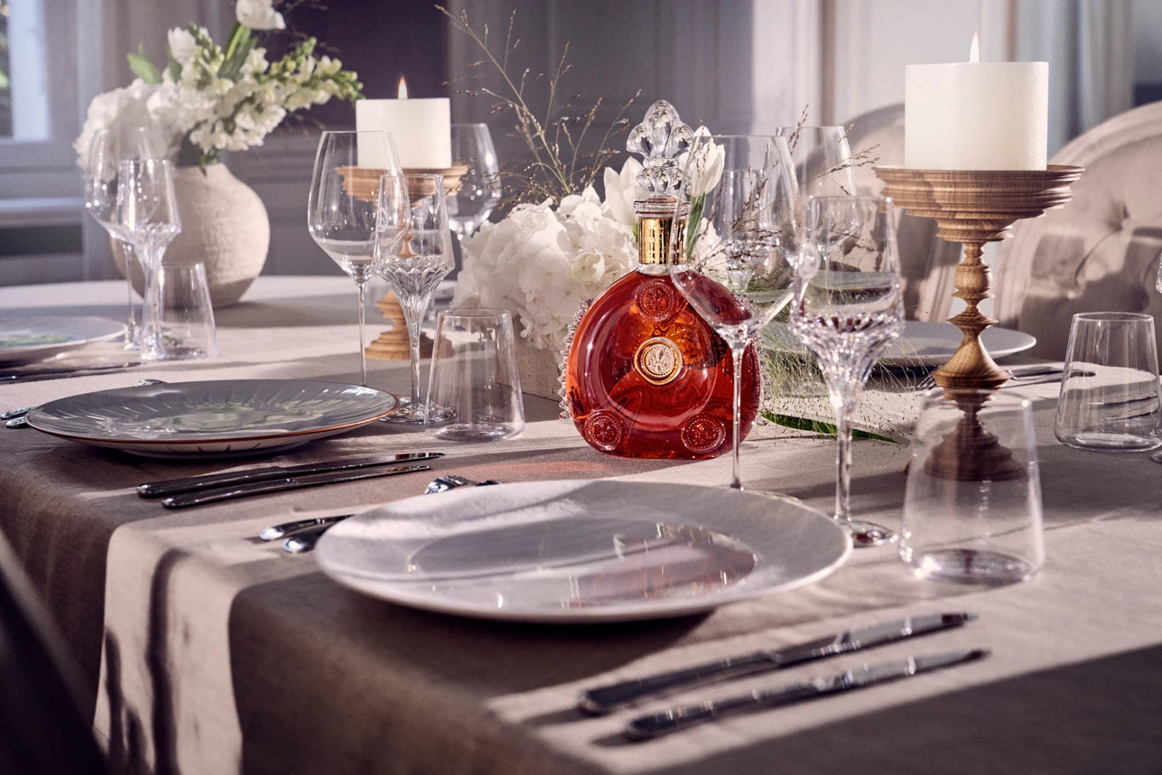 Bouteille de cognac Louis XIII mise en avant au cœur d’un dressage raffiné, symbole de luxe, de prestige et d’art de vivre