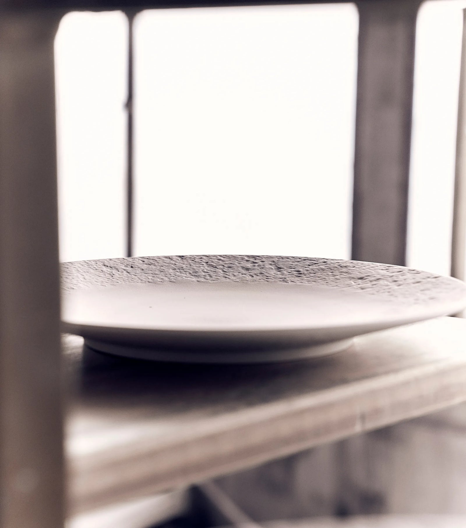 Assiette de luxe et artistique de la collection Ode à la matière posée sur une étagère d’atelier